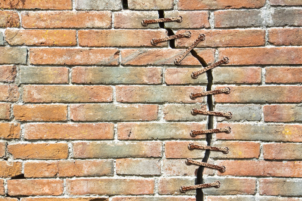 Cracked brick wall with a metal seam